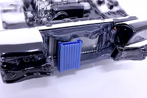 Close-up of a painted RC car interior detail set featuring an engine bay and a blue intercooler mounted in the front.