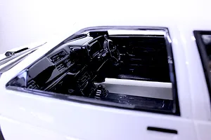 Close-up of a detailed black RC car interior with dashboard and steering wheel inside a white body shell.