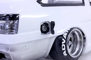 Close-up view of a white RC drift car body showing rear wheel, tire with Advan lettering, tail light, and fuel filler cap detail.