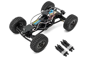 Top-down studio view of a 1/24 scale RC rock crawler chassis with exposed electronics and four separate shocks placed alongside it on a white background.