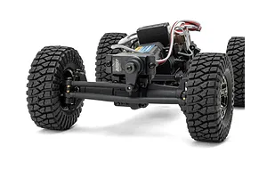 Close-up front view of the RC rock crawler chassis showing the steering servo, axle, and knobby tires against a white background.