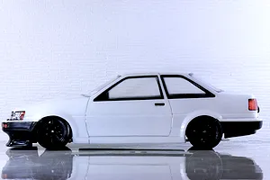 Side profile view of a white Toyota AE86 Corolla Levin RC car body with black wheels and bumpers.