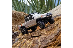 Axial SCX30 Toyota Tacoma RC rock crawler driving over outdoor rocks and dirt