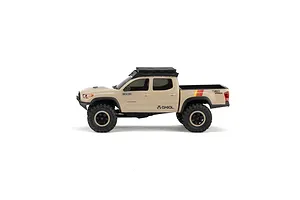 Side profile view of the Axial SCX30 Toyota Tacoma RC rock crawler in brown with a black roof rack and chunky off-road tires on a white background.