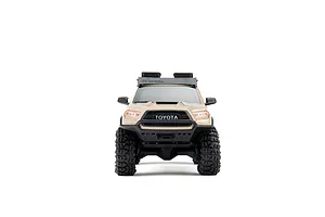 Front view of the Axial SCX30 Toyota Tacoma RC rock crawler in brown, featuring a roof rack and chunky off-road tires against a white background.