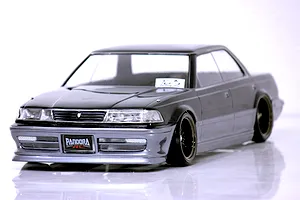 Front three-quarter view of a painted Pandora RC Toyota Mark2 JZX81 drift body shell mounted on an RC chassis with custom wheels against a white studio background.