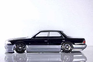 Side profile of a painted black and silver Toyota Mark II RC drift car body shell on a white studio background.