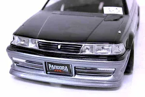 Close-up front view of a black and silver RC drift car body shell with Pandora RC license plate against a white background.