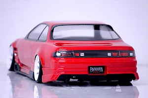 Rear three-quarter view of a painted red S14 Silvia RC drift car body with white wheels and Pandora RC license plate on a light surface.