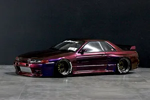 Custom painted purple and bronze RC drift car body modeled after a Nissan Skyline GT-R R32 on a dark studio floor.
