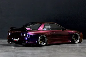Rear three-quarter studio view of a painted Pandora RC Nissan Skyline R32 GT-R body shell with custom wheels in purple finish.