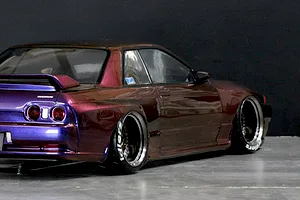 Rear three-quarter view of a custom painted RC car body modeled after a Nissan Skyline GT-R with wide wheels and deep dish rims.