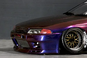 Close-up front quarter view of a custom painted purple and bronze metallic RC drift car body shell mounted on a chassis with custom wheels.