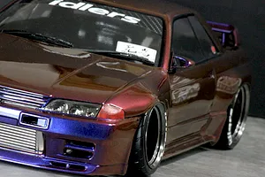 Close-up of a custom painted RC drift car body styled as a Nissan Skyline GT-R with colour-shifting purple and bronze finish.