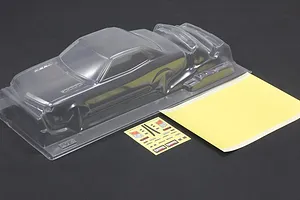 Unpainted clear polycarbonate RC car body shell with a mask sheet and decal sheet on a dark background.
