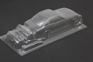 Unpainted clear polycarbonate RC car body shell with separate bumper and grille parts on a dark background.