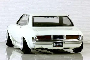 Rear view of a white Pandora RC Toyota Celica 1600GT body shell on a gloss surface against a white brick wall background.
