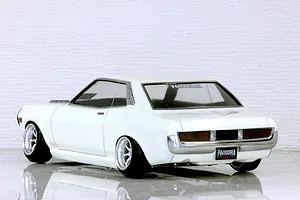 Rear-three-quarter studio view of a white Toyota Celica 1600GT RC drift car body shell on a reflective surface.
