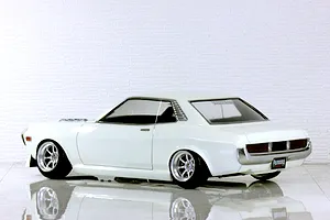 Rear three-quarter view of a white Toyota Celica RC drift car body shell with custom wheels and reflective floor.