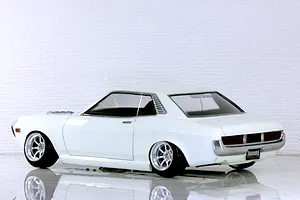 Side view of a white Toyota Celica 1600GT RC drift car body shell on a reflective white studio surface.