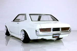 Rear three-quarter view of a painted white Toyota Celica 1600GT RC drift car body on a reflective white studio surface.