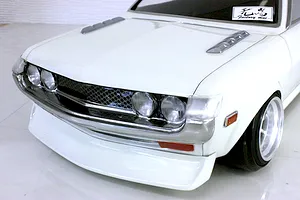 Close-up front view of a white Toyota Celica RC drift car body shell featuring a detailed chrome grille and quad headlights.