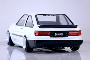 Rear three-quarter view of a white Toyota AE86 Corolla Levin RC drift car body shell on a reflective white studio surface.