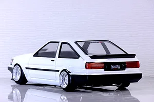 Rear-three-quarter view of a white RC drift car body styled like a Toyota AE86 Corolla Levin on a reflective white surface.
