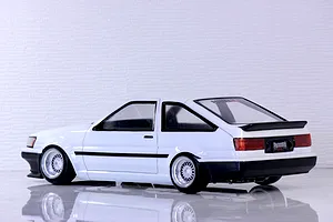 Side-rear profile view of a painted white Toyota AE86 Corolla Levin RC drift car body shell with black bumpers and mesh wheels.