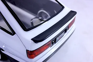 Close-up view of the rear end of a white RC drift car body showing the trunk spoiler, taillights, and rear window.