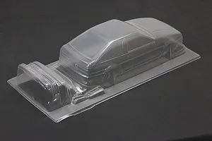 Unpainted clear polycarbonate RC car body shell of a Toyota AE86 Sprinter Trueno 3-door on a dark surface.