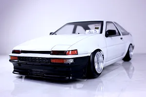 Low angle front-three-quarter view of a white RC drift car body styled after a Toyota AE86 Trueno with custom deep dish wheels.