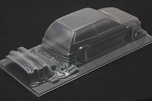 Unpainted clear polycarbonate RC body shell of a Honda Civic Si with separate bumper and accessory parts on a dark background.