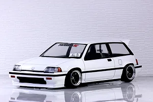 White Honda Civic Si RC drift body shell mounted on an RC chassis against a white brick wall background.
