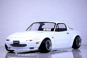 Studio shot of a white Pandora RC Mazda Eunos Roadster body shell mounted on an RC chassis with custom wheels against a light background.