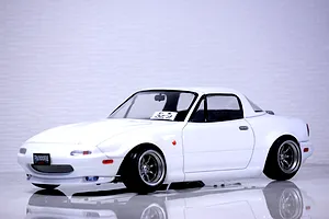 A painted white Mazda Eunos Roadster NA RC body shell mounted on a chassis with custom wheels against a neutral background.
