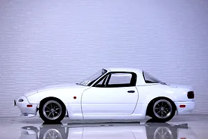 Side profile view of a painted white Mazda Eunos Roadster NA RC body shell mounted on a chassis with multi-spoke wheels.
