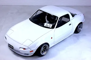 White Mazda Eunos Roadster NA RC drift car body shell mounted on a chassis with custom wheels against a neutral background.