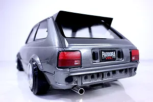 Rear three-quarter studio view of a grey Pandora RC Toyota Starlet KP61 body shell featuring custom wheels and a rear spoiler.