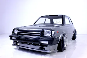 Front three-quarter view of a grey RC drift car body mounted on a chassis against a plain white background.