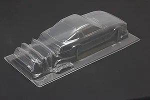 Unpainted clear polycarbonate RC car body shell for a Mazda Savanna RX-7 on a dark surface.