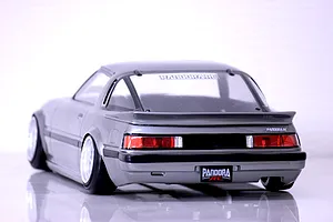 Rear view of the painted Mazda Savanna RX-7 SA22C RC body shell by Pandora RC in silver on a white surface.