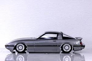 Side profile of a grey Pandora RC Mazda Savanna RX-7 SA22C body shell mounted on an RC chassis with wire-mesh wheels.