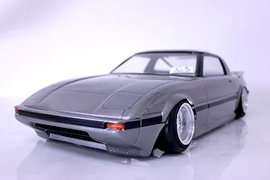 Painted grey Mazda Savanna RX-7 RC drift car body shell mounted on a chassis with custom wheels against a white background.