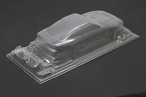 Unpainted clear polycarbonate RC drift car body shell viewed from the rear three-quarters on a dark surface.