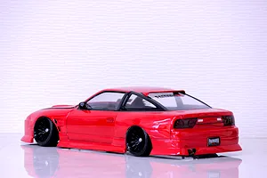 Rear quarter view of a red Pandora RC RPS13 180SX drift car body shell with black multi-spoke wheels on a glossy white surface.