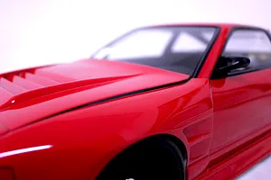 Close-up of the red painted front fender and vented hood of a Pandora RC 180SX body shell.