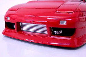 Close-up front view of a red RC drift car body showing the front bumper, pop-up headlight outlines, and a detailed intercooler.