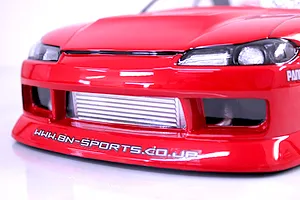 Close-up of the front end of a red RC drift car body shell showing the bumper, headlights, and intercooler.