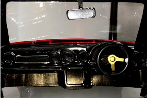 Close-up of a detailed RC car interior dashboard with a steering wheel and rearview mirror inside a transparent body shell.